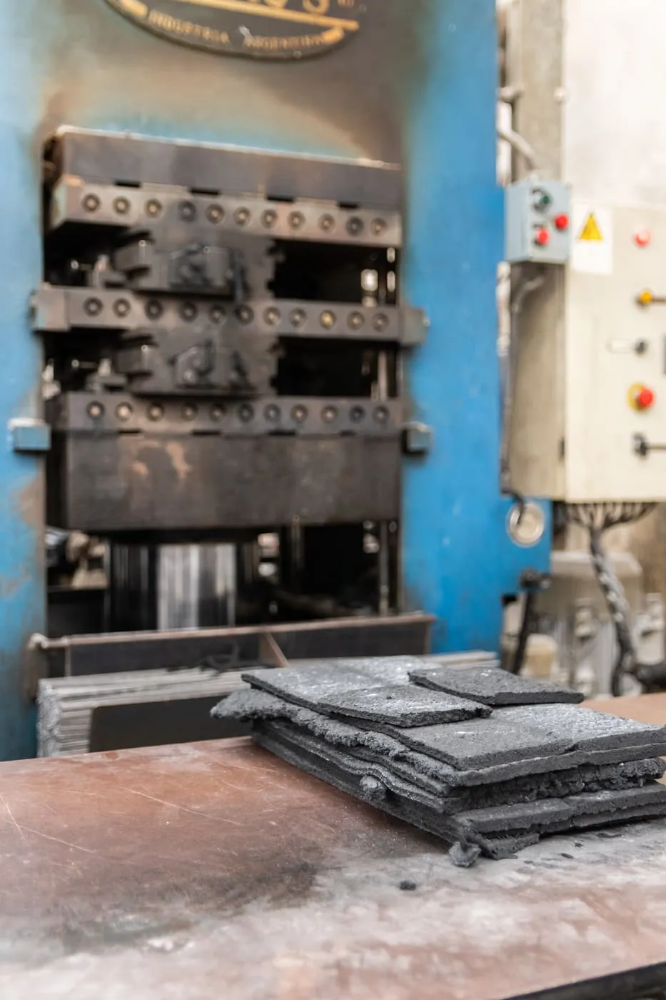 Prensa hidráulica industria argentina con materia prima de goma en primer plano